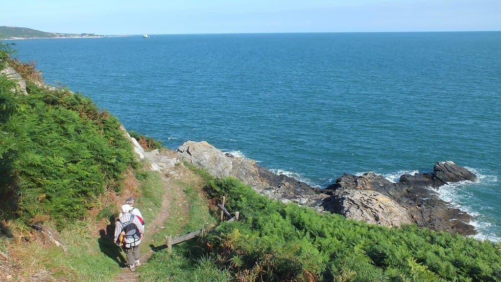 Un sentier littoral serpentant au-dessus des rochers et de la mer.